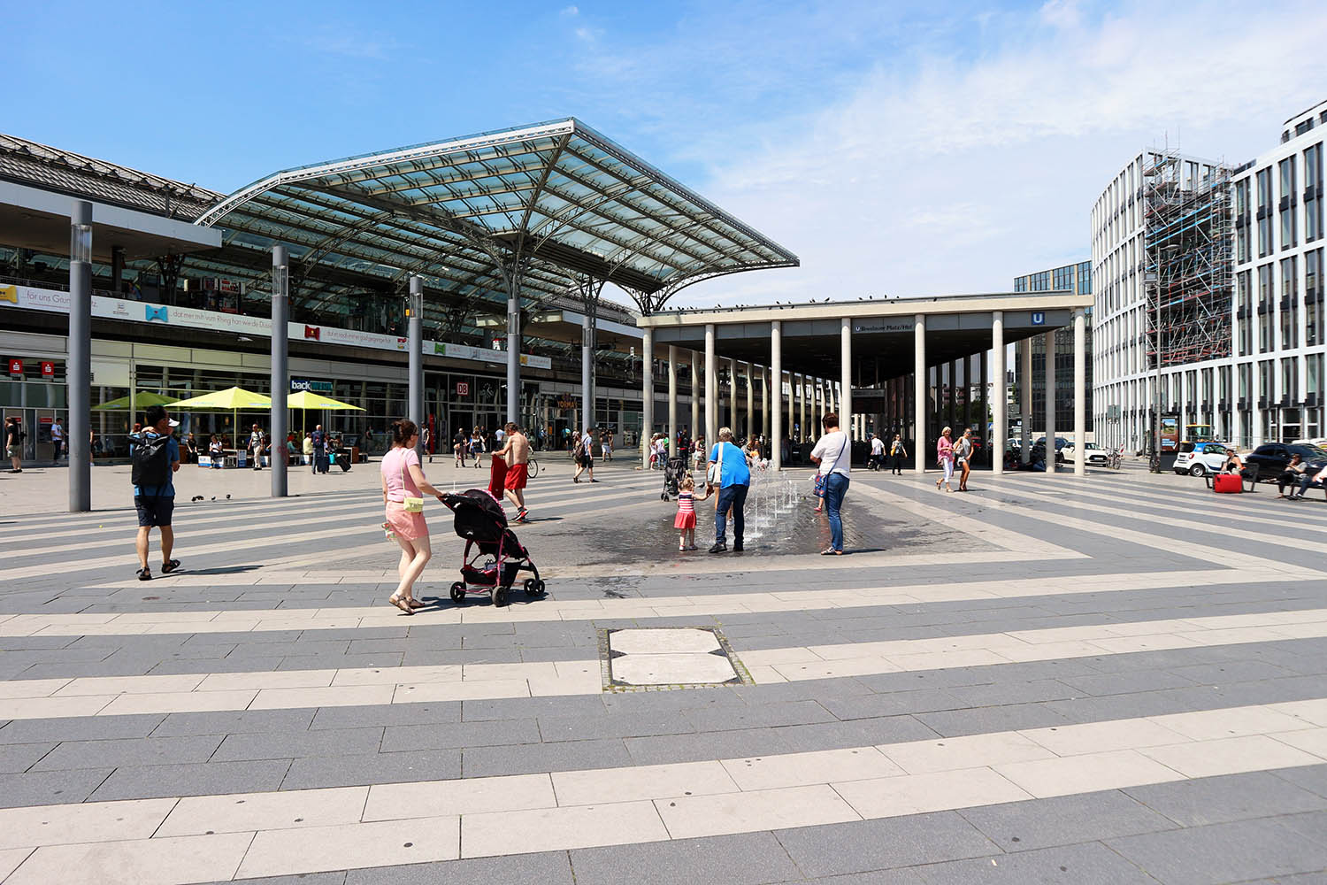 Breslauer Platz, Completion of the New Design, 2013. Designed by Büder + Metzel Architekten, Brühl/Cologne. Breslauer Platz is a square on the northeast side of the central train station. The transformation into an urban space took some time. The work done by Kai Büder and Manfred Metzel resulted in greater transparency and a clearly designed, public space with more room for pedestrians. Under each of the three column-supported pavilion roofs of the station, a weather-protected extension of the front plaza areas has arisen, as an entrance to the subway station and to the central train station. 