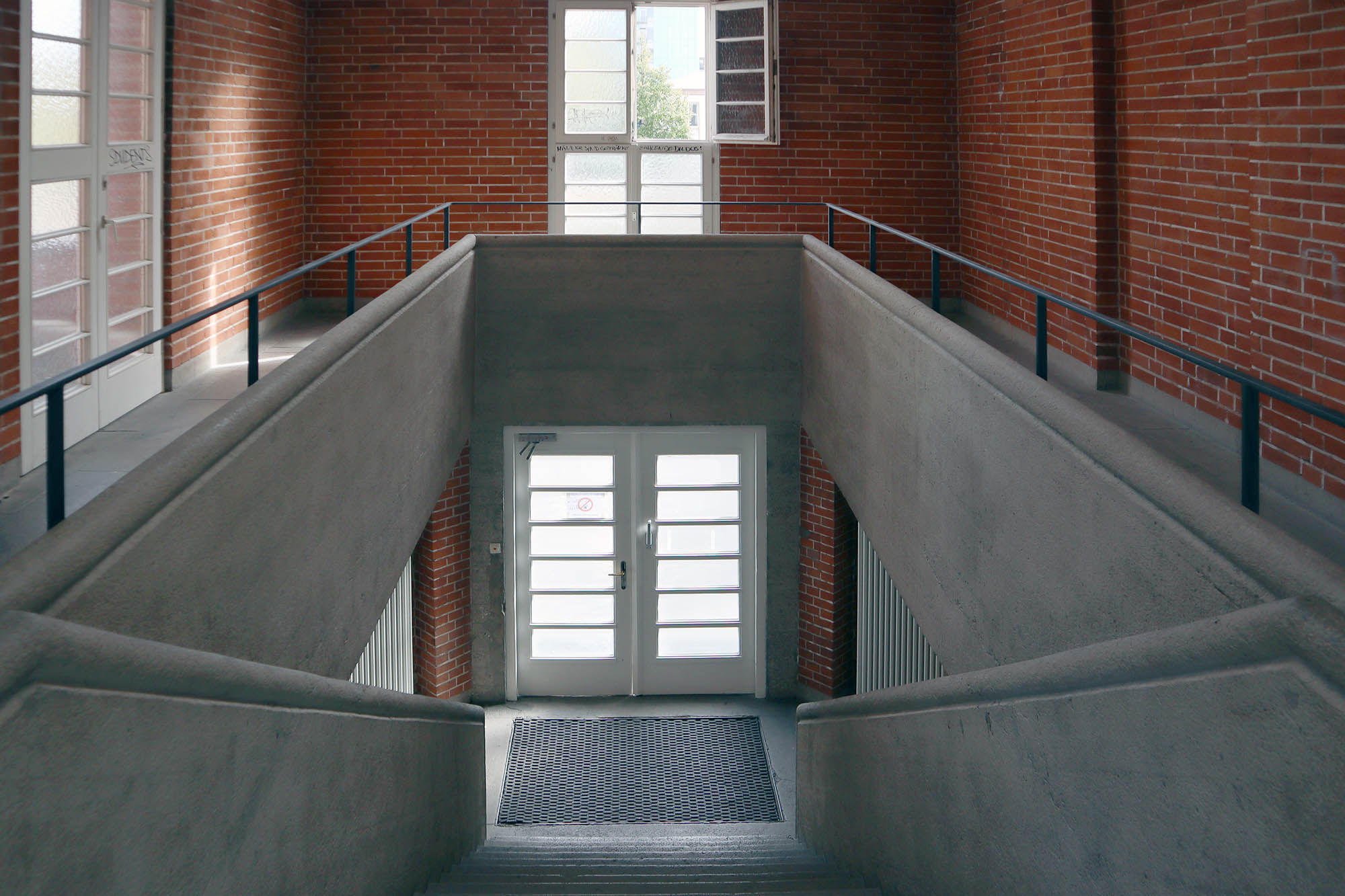 Beton und Ziegelstein kontrastieren auch in den beiden Treppenräumen und im imposanten Gymnastiksaal unter der Tribüne.