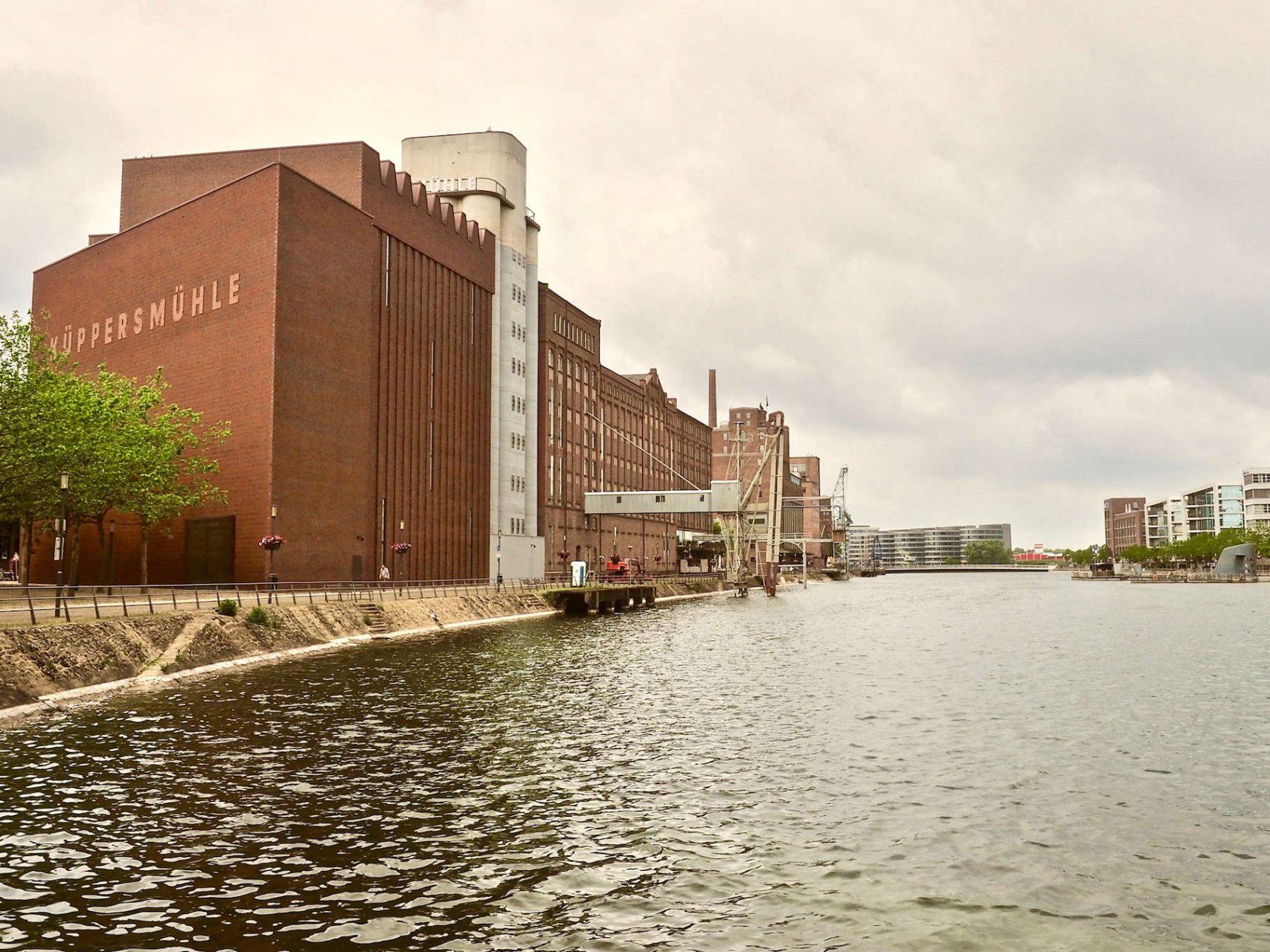 Masterplan.. Der Innenhafen von Duisburg, durch einen Kanal mit dem Rhein verbunden, war lange von Getreidemühlen gesäumt und galt als der Brotkorb des Ruhrgebietes. Um den Niedergang seit den siebziger Jahren des letzten Jahrhunderts aufzuhalten, beauftragte die Stadt um die Jahrtausendwende Norman Foster mit einem Masterplan. Inwischen sind die Promenaden am Wasser mit Häusern zum Wohnen, Arbeiten und Ausgehen bestückt und die alten Fabriken haben neue Funktionen – mit der Küppersmühle als Highlight. 