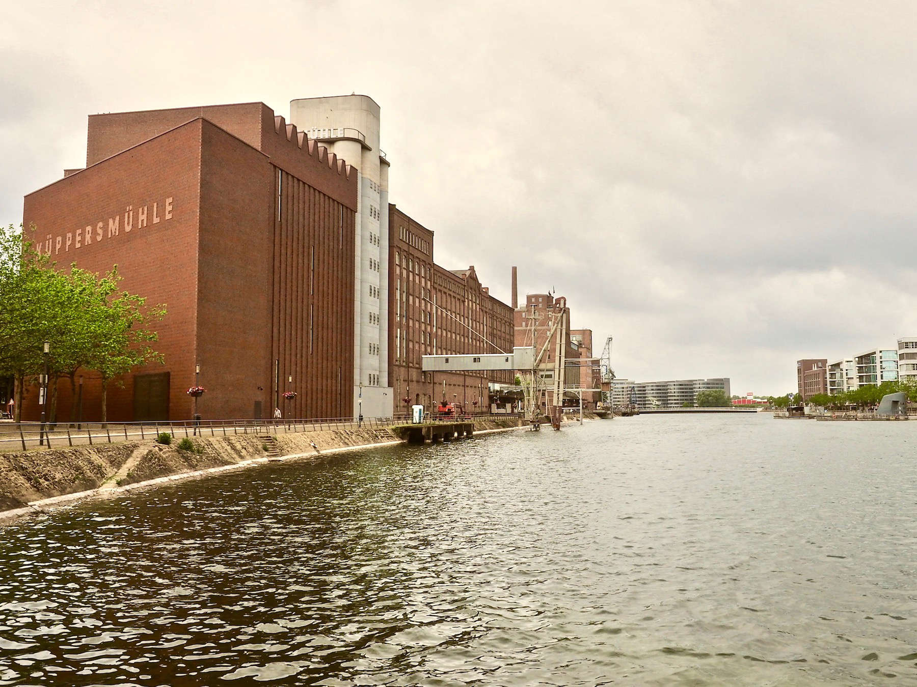 Der Innenhafen von Duisburg, durch einen Kanal mit dem Rhein verbunden, war lange von Getreidemühlen gesäumt und galt als der Brotkorb des Ruhrgebietes. Um den Niedergang seit den siebziger Jahren des letzten Jahrhunderts aufzuhalten, beauftragte die Stadt um die Jahrtausendwende Norman Foster mit einem Masterplan. Inwischen sind die Promenaden am Wasser mit Häusern zum Wohnen, Arbeiten und Ausgehen bestückt und die alten Fabriken haben neue Funktionen – mit der Küppersmühle als Highlight. 