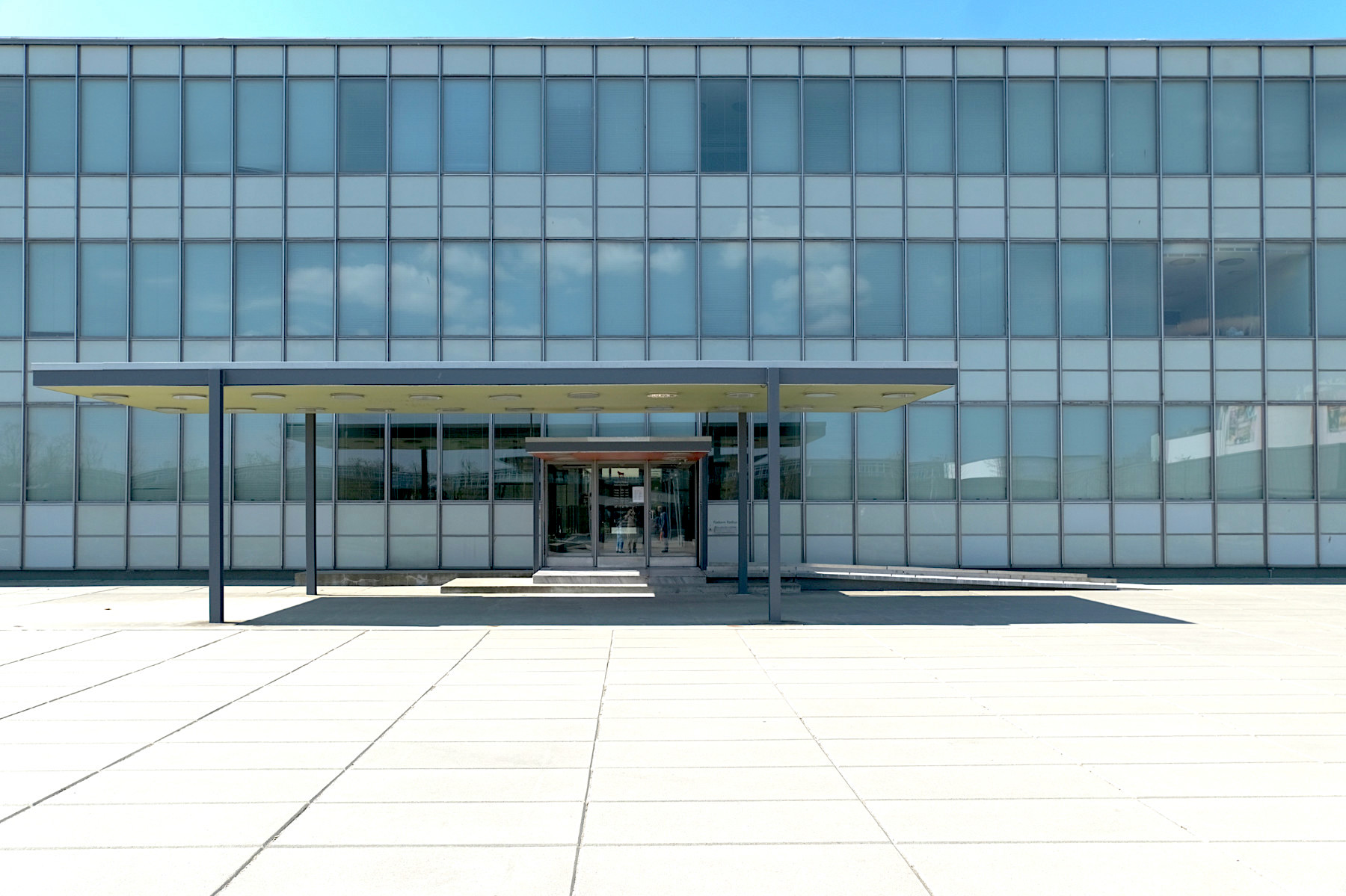 Die straffe Geometrie und die leichten Vorhangfassaden aus Stahl und Glas zeugen von Arne Jacobsens Hinwendung zum internationalen Stil, sowie seinem Wissen um Eero Saarinens ikonisches General Motors Technical Center in Warren (USA).