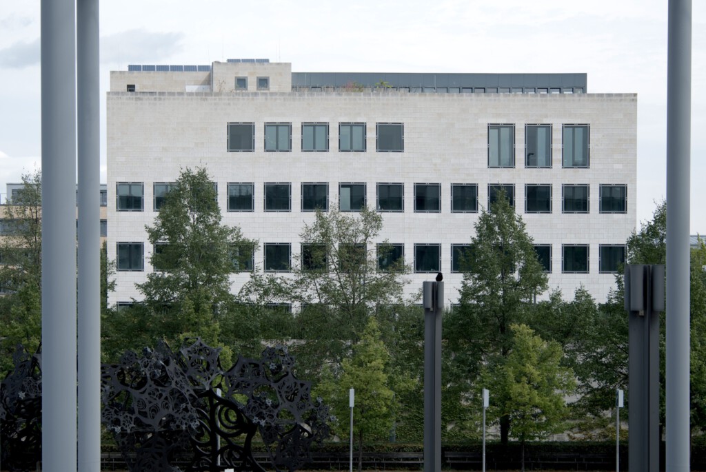 Der Neubau von Oswald Mathias Ungers steht auf dem ehemaligen DWM-Areal beim heutigen ZKM; Einweihung 1998. Typologisch als „Stadtpalais“ gedacht, mit klarer Geometrie und streng gefasster Adresse. In Sichtweite von ZKM und „Platz der Menschenrechte“ verknüpft der Bau Justiz mit Stadtraum. 